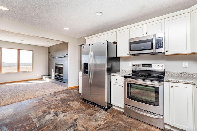 2717 88th Ave S, Fargo, ND 58104 - kitchen featuring stainless steel appliances, open floor plan, stone finish floors, white cabinets, and a textured ceiling