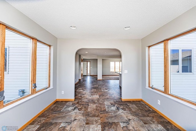 2717 88th Ave S, Fargo, ND 58104 - corridor with arched walkways, baseboards, stone finish flooring, a textured ceiling, and recessed lighting