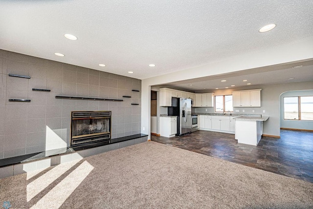 2717 88th Ave S, Fargo, ND 58104 - unfurnished living room featuring a tiled fireplace, recessed lighting, a sink, baseboards, and a textured ceiling