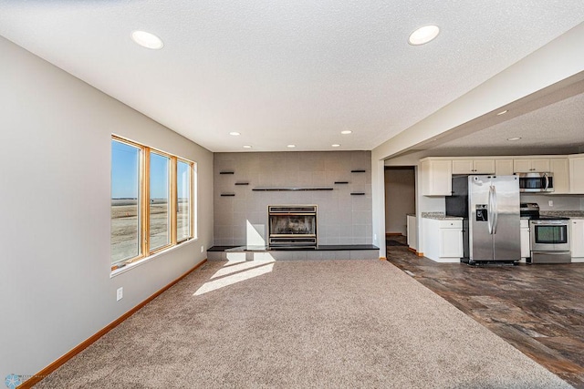 2717 88th Ave S, Fargo, ND 58104 - unfurnished living room featuring baseboards, a tile fireplace, recessed lighting, and a textured ceiling