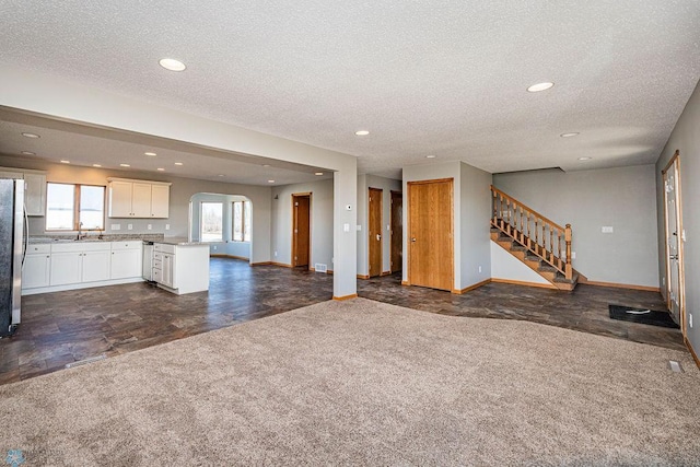 2717 88th Ave S, Fargo, ND 58104 - unfurnished living room featuring baseboards, a textured ceiling, recessed lighting, stairway, and dark carpet