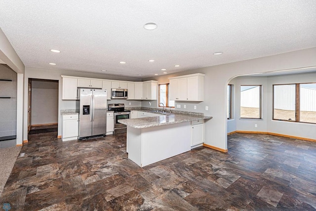 2717 88th Ave S, Fargo, ND 58104 - kitchen with appliances with stainless steel finishes, a sink, a peninsula, baseboards, and a textured ceiling