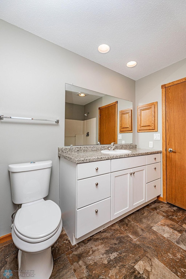 2717 88th Ave S, Fargo, ND 58104 - full bathroom featuring vanity, toilet, stone finish floors, and a textured ceiling