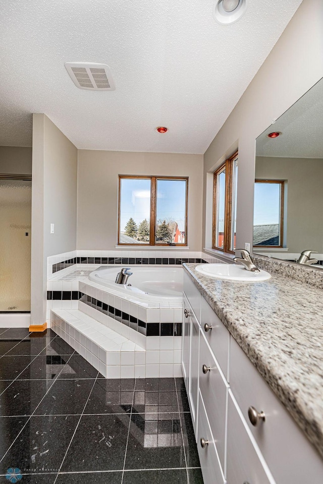 2717 88th Ave S, Fargo, ND 58104 - bathroom with vanity, a garden tub, plenty of natural light, granite floors, and a textured ceiling
