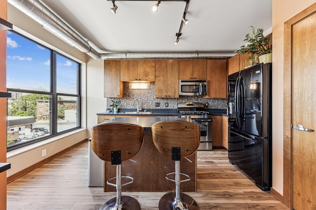 15 Franklin Ave Unit 312, Minneapolis, MN 55404 - kitchen with appliances with stainless steel finishes, dark countertops, a sink, brown cabinets, and decorative backsplash