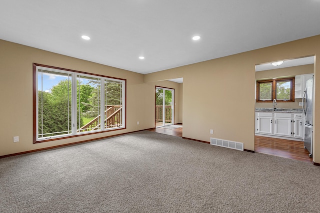 1930 6th Ave NE, Owatonna, MN 55060 - unfurnished living room with a sink, dark carpet, baseboards, and recessed lighting