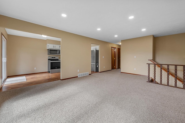 1930 6th Ave NE, Owatonna, MN 55060 - unfurnished living room featuring light colored carpet, baseboards, and recessed lighting