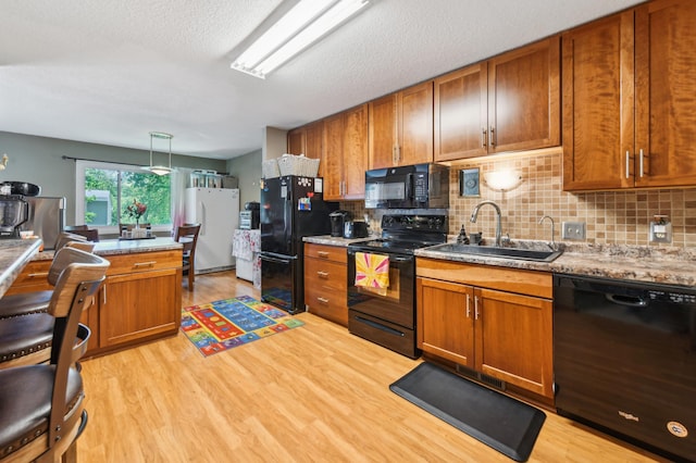 1351 4th St W, Hastings, MN 55033 - kitchen featuring black appliances, a sink, decorative backsplash, brown cabinetry, and a textured ceiling
