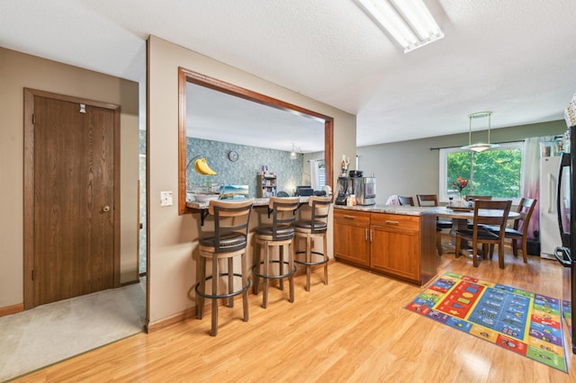1351 4th St W, Hastings, MN 55033 - bar with light wood-style flooring, freestanding refrigerator, and a textured ceiling