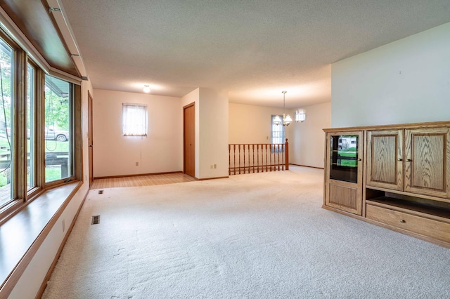 415 2nd Ave SE, Pelican Rapids, MN 56572 - empty room with light carpet, a chandelier, baseboards, and a textured ceiling