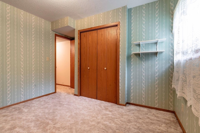 415 2nd Ave SE, Pelican Rapids, MN 56572 - unfurnished bedroom with wallpapered walls, a closet, carpet floors, and a textured ceiling