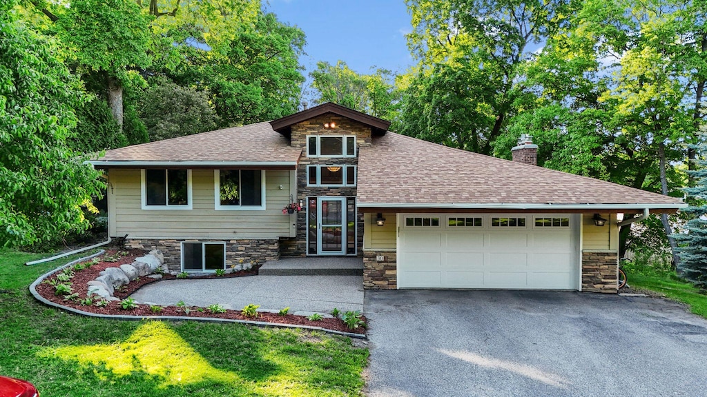 30 Tonka Bay Ln, Tonka Bay, MN 55331 - split level home featuring stone siding, driveway, a chimney, and a garage