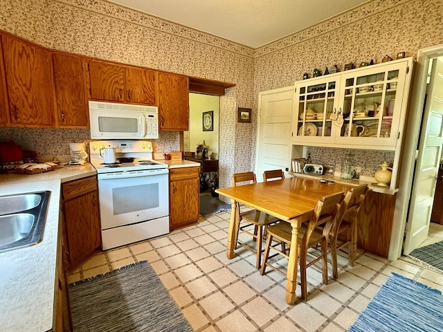 2100 Trott Ave SW, Willmar, MN 56201 - kitchen featuring white appliances, wallpapered walls, a sink, light countertops, and backsplash