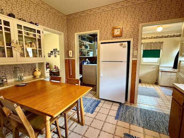 2100 Trott Ave SW, Willmar, MN 56201 - kitchen with freestanding refrigerator, washer / clothes dryer, wallpapered walls, glass insert cabinets, and light floors