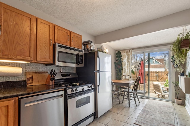 5236 42nd Ave S, Minneapolis, MN 55417 - kitchen featuring stainless steel appliances, backsplash, light tile patterned floors, brown cabinetry, and a textured ceiling