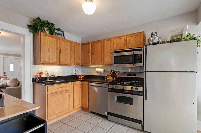 5236 42nd Ave S, Minneapolis, MN 55417 - kitchen featuring appliances with stainless steel finishes, tasteful backsplash, a textured ceiling, light tile patterned floors, and dark countertops