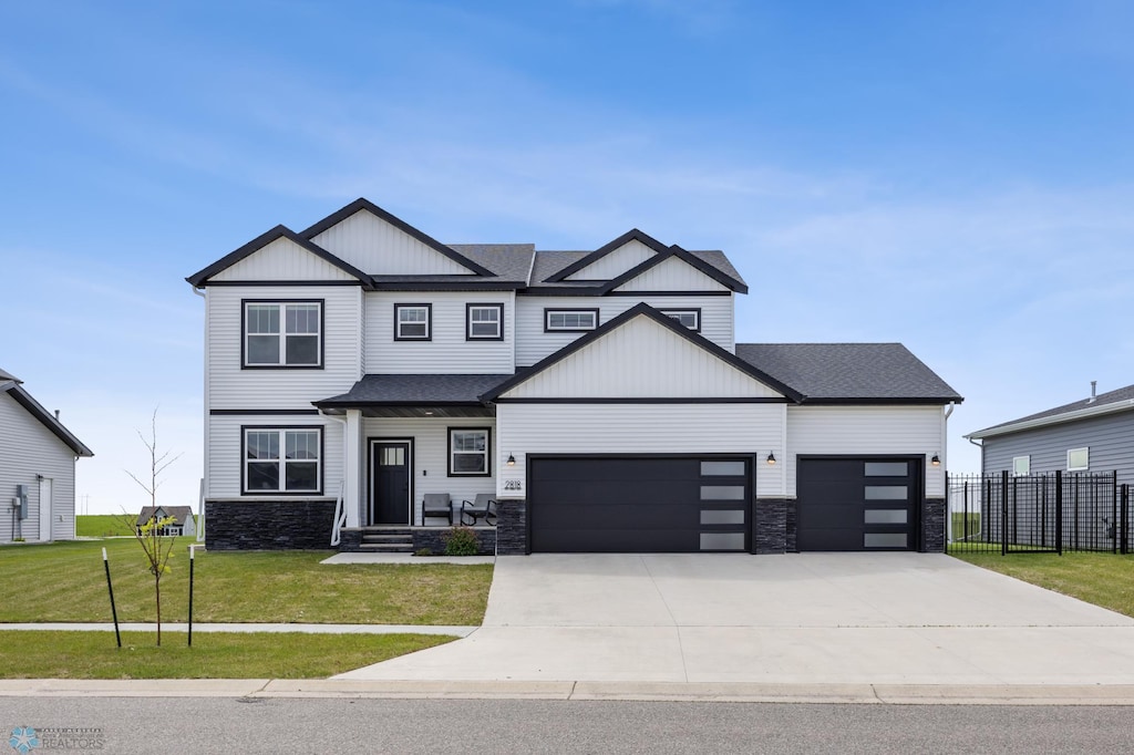 2818 14th St W, West Fargo, ND 58078 - view of front of house with a garage, stone siding, driveway, and board and batten siding