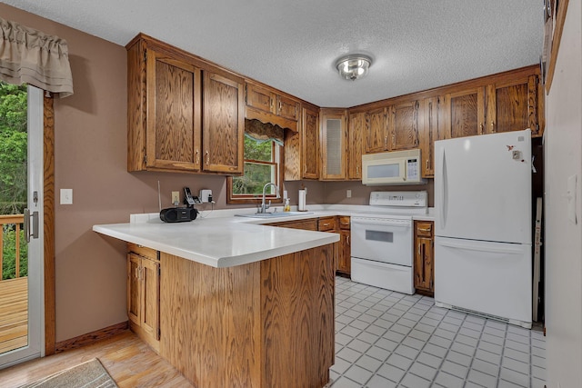 11236 207th Ave NW, Elk River, MN 55330 - kitchen featuring white appliances, a peninsula, a sink, brown cabinetry, and light countertops