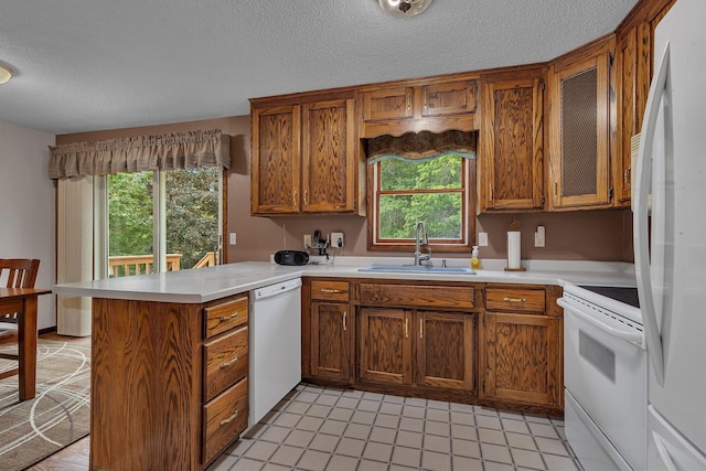 11236 207th Ave NW, Elk River, MN 55330 - kitchen with white appliances, a sink, a peninsula, brown cabinetry, and a textured ceiling