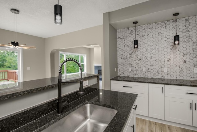 7658 Silver Lake Rd, Mounds View, MN 55112 - kitchen featuring a sink, backsplash, decorative light fixtures, and white cabinetry