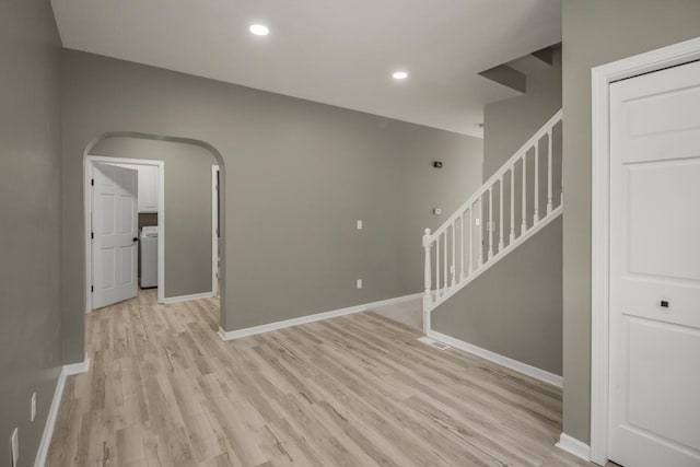 7658 Silver Lake Rd, Mounds View, MN 55112 - unfurnished room featuring stairway, light wood-style flooring, washer / clothes dryer, baseboards, and arched walkways