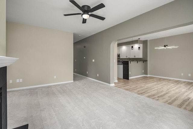 7658 Silver Lake Rd, Mounds View, MN 55112 - unfurnished living room with ceiling fan, baseboards, arched walkways, light carpet, and light wood finished floors