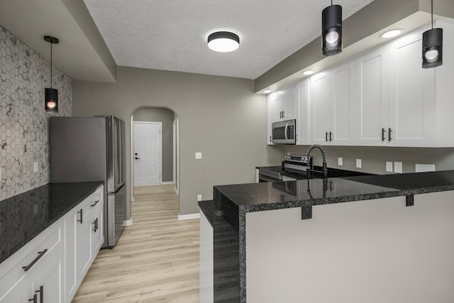 7658 Silver Lake Rd, Mounds View, MN 55112 - kitchen with stainless steel appliances, arched walkways, a peninsula, light wood-type flooring, and a breakfast bar