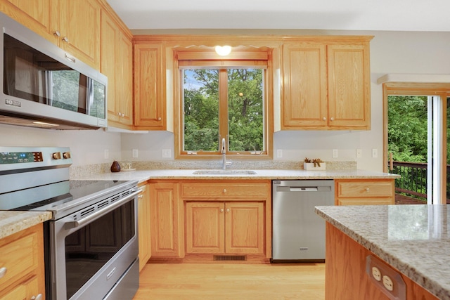 20383 Erickson Ct, Farmington, MN 55024 - kitchen featuring appliances with stainless steel finishes, a sink, light brown cabinetry, light wood-style flooring, and plenty of natural light