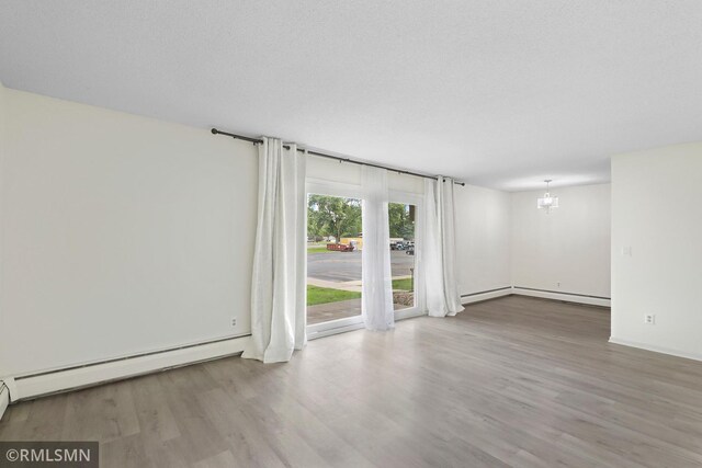 2800 Hillsboro Ave N Unit 108, New Hope, MN 55427 - unfurnished room featuring wood finished floors, a chandelier, and a baseboard heating unit