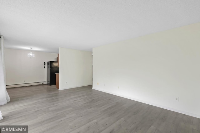 2800 Hillsboro Ave N Unit 108, New Hope, MN 55427 - unfurnished room featuring a baseboard radiator, wood finished floors, baseboards, a chandelier, and a textured ceiling