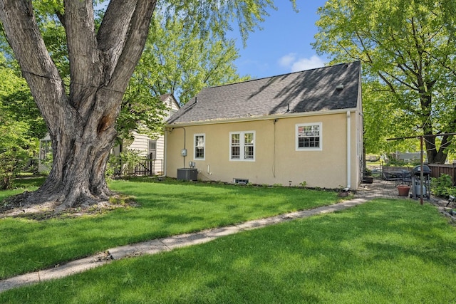 5604 14th Ave S, Minneapolis, MN 55417 - rear view of property featuring stucco siding, central air condition unit, a lawn, and roof with shingles