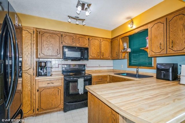 17551 London St NE, Ham Lake, MN 55304 - kitchen with black appliances, a sink, brown cabinetry, light countertops, and a peninsula