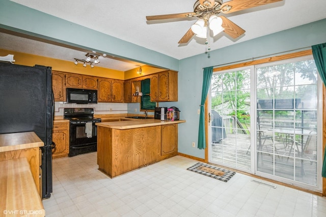 17551 London St NE, Ham Lake, MN 55304 - kitchen featuring black appliances, brown cabinetry, a peninsula, light countertops, and a sink