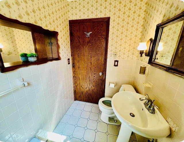 150 Park St W, South Saint Paul, MN 55075 - bathroom featuring wallpapered walls, tile walls, a wainscoted wall, toilet, and a sink