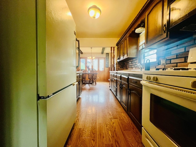 150 Park St W, South Saint Paul, MN 55075 - kitchen with white appliances, wood finished floors, light countertops, dark brown cabinetry, and a sink