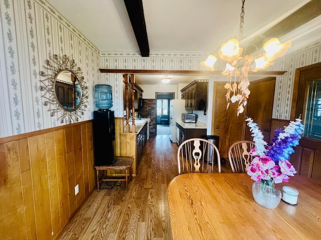 150 Park St W, South Saint Paul, MN 55075 - dining space featuring a chandelier, wood finished floors, wallpapered walls, a wainscoted wall, and beam ceiling