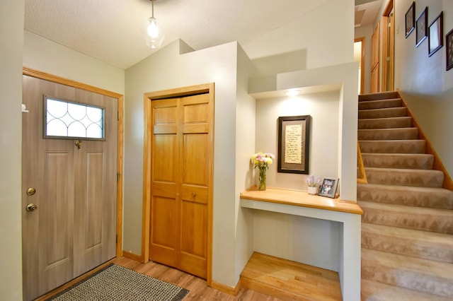 1518 4th Ave N, Sartell, MN 56377 - foyer entrance with lofted ceiling, light wood-style floors, stairs, baseboards, and a textured ceiling