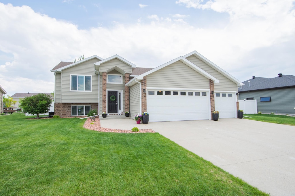 4513 12th St W, West Fargo, ND 58078 - split level home with driveway, a garage, a front lawn, and brick siding