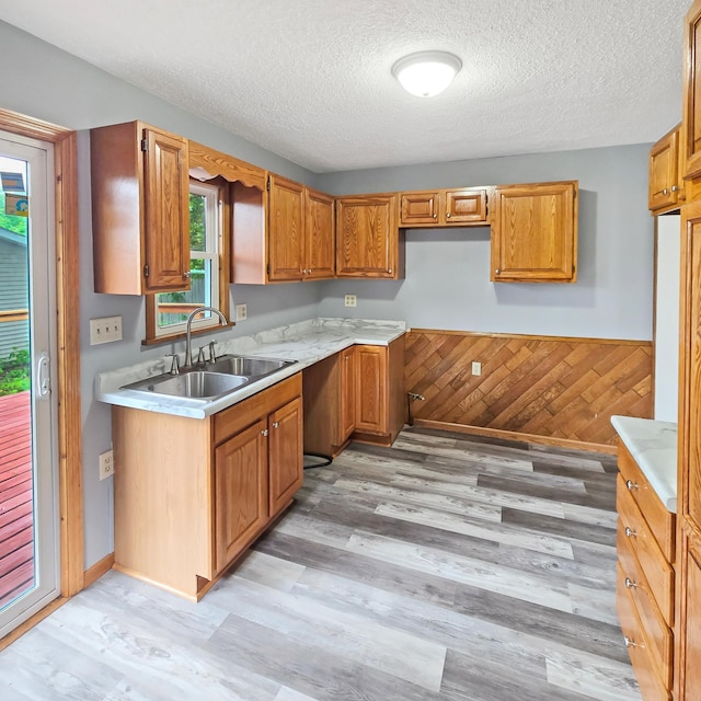 2718 Morgan Ave N, Minneapolis, MN 55411 - kitchen with a sink, light wood-type flooring, light countertops, a textured ceiling, and brown cabinetry