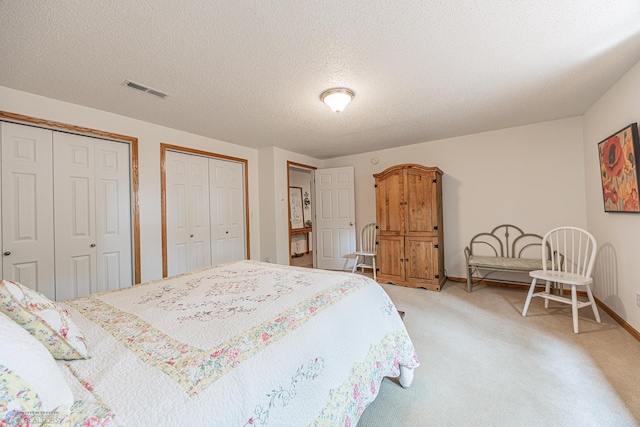 5916 Elm St N, Moorhead, MN 56560 - bedroom featuring multiple closets, light carpet, baseboards, and a textured ceiling