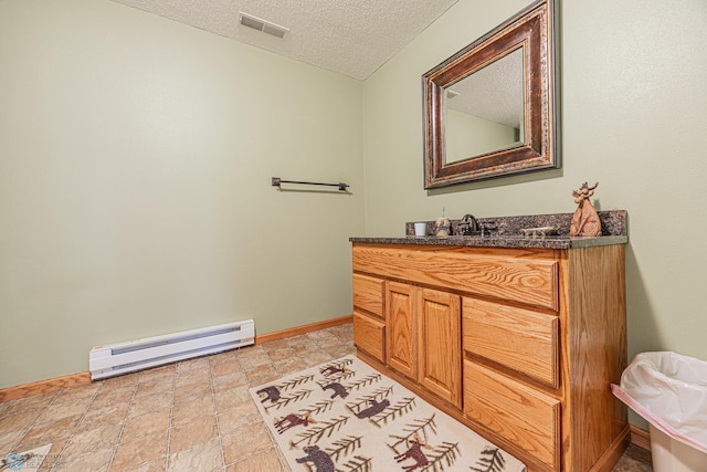 5916 Elm St N, Moorhead, MN 56560 - bathroom featuring a baseboard heating unit, vanity, a textured ceiling, baseboards, and stone finish flooring