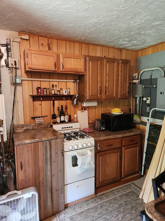35270 Bear Creek Rd, Partridge Twp, MN 55704 - kitchen with black microwave, white gas range, brown cabinets, wooden walls, and a textured ceiling