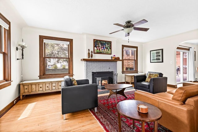 4031 Regent St, Duluth, MN 55804 - living room featuring light wood-style flooring, ceiling fan, arched walkways, a fireplace, and baseboards
