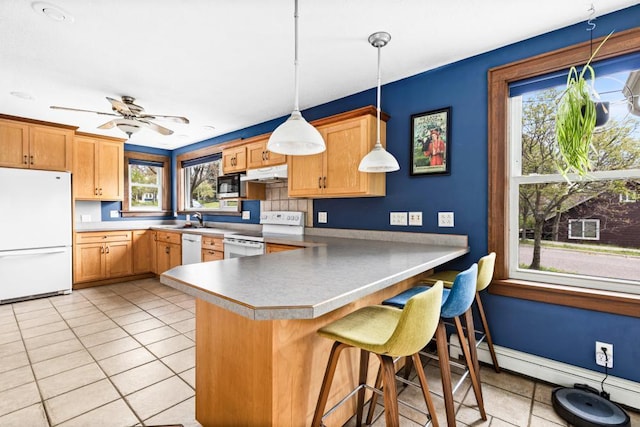 4031 Regent St, Duluth, MN 55804 - kitchen featuring white appliances, under cabinet range hood, light tile patterned flooring, a peninsula, and a sink