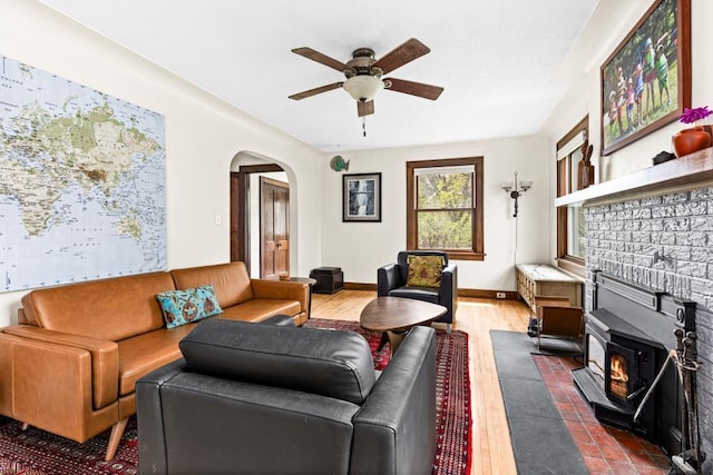 4031 Regent St, Duluth, MN 55804 - living room featuring a ceiling fan, arched walkways, a wood stove, wood finished floors, and baseboards