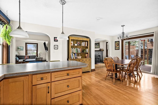 4031 Regent St, Duluth, MN 55804 - kitchen featuring arched walkways, light wood-type flooring, a chandelier, a fireplace, and decorative light fixtures