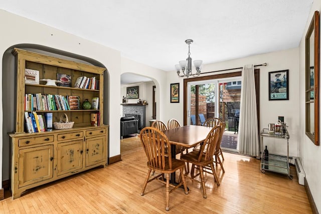 4031 Regent St, Duluth, MN 55804 - dining room featuring arched walkways, a chandelier, a brick fireplace, light wood-style floors, and baseboards