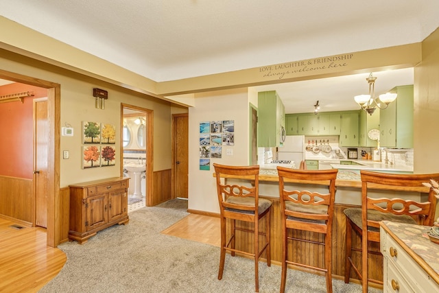 2816 29th Ave NE, Saint Anthony, MN 55418 - dining area with a chandelier, a wainscoted wall, wooden walls, light carpet, and light wood-style floors