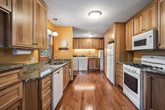 5404 Welcome Ave N, Crystal, MN 55429 - kitchen featuring white appliances, washer and clothes dryer, a sink, dark wood-style floors, and dark stone countertops
