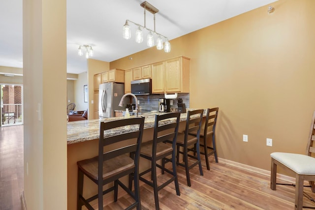 16154 Main Ave SE # 120, Prior Lake, MN 55372 - kitchen featuring light brown cabinets, stainless steel appliances, decorative backsplash, light wood-style floors, and a peninsula